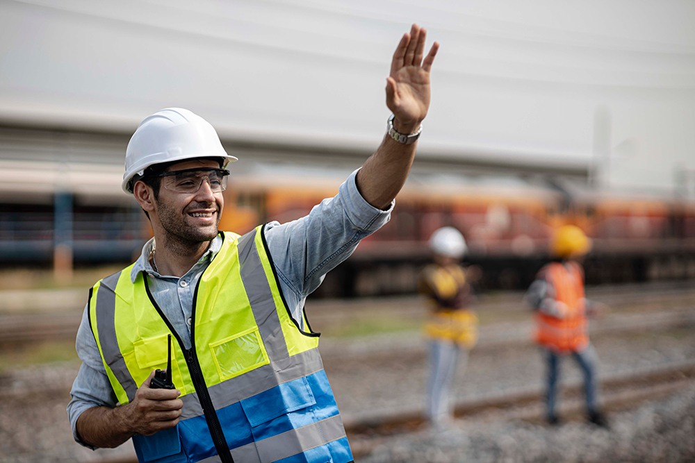 man in railroad field waving